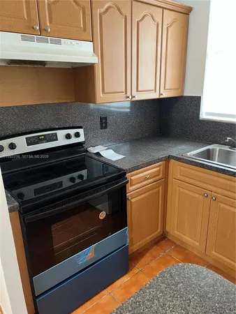 a kitchen with granite countertop a stove a sink and a microwave