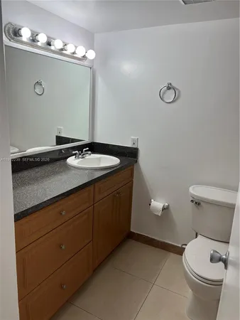 a bathroom with a granite countertop sink a toilet and a mirror