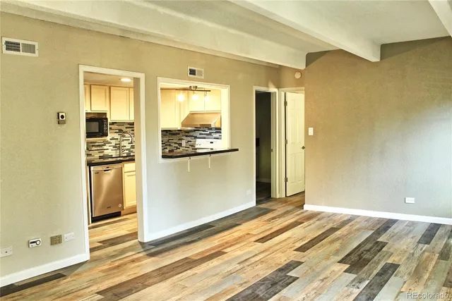a view of a hallway with wooden floor and a bathroom