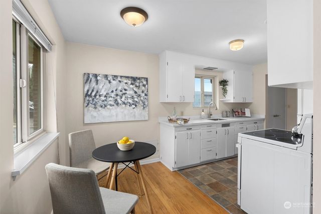 a kitchen with stainless steel appliances granite countertop a sink a stove a dining table and chairs