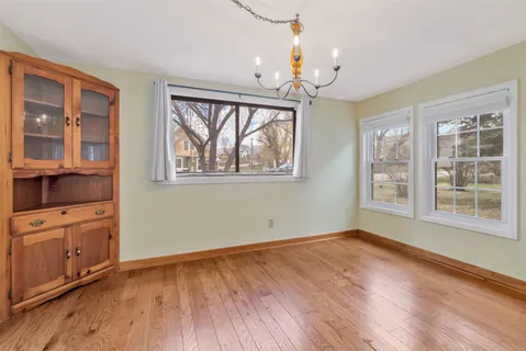 an empty room with wooden floor cabinet and windows