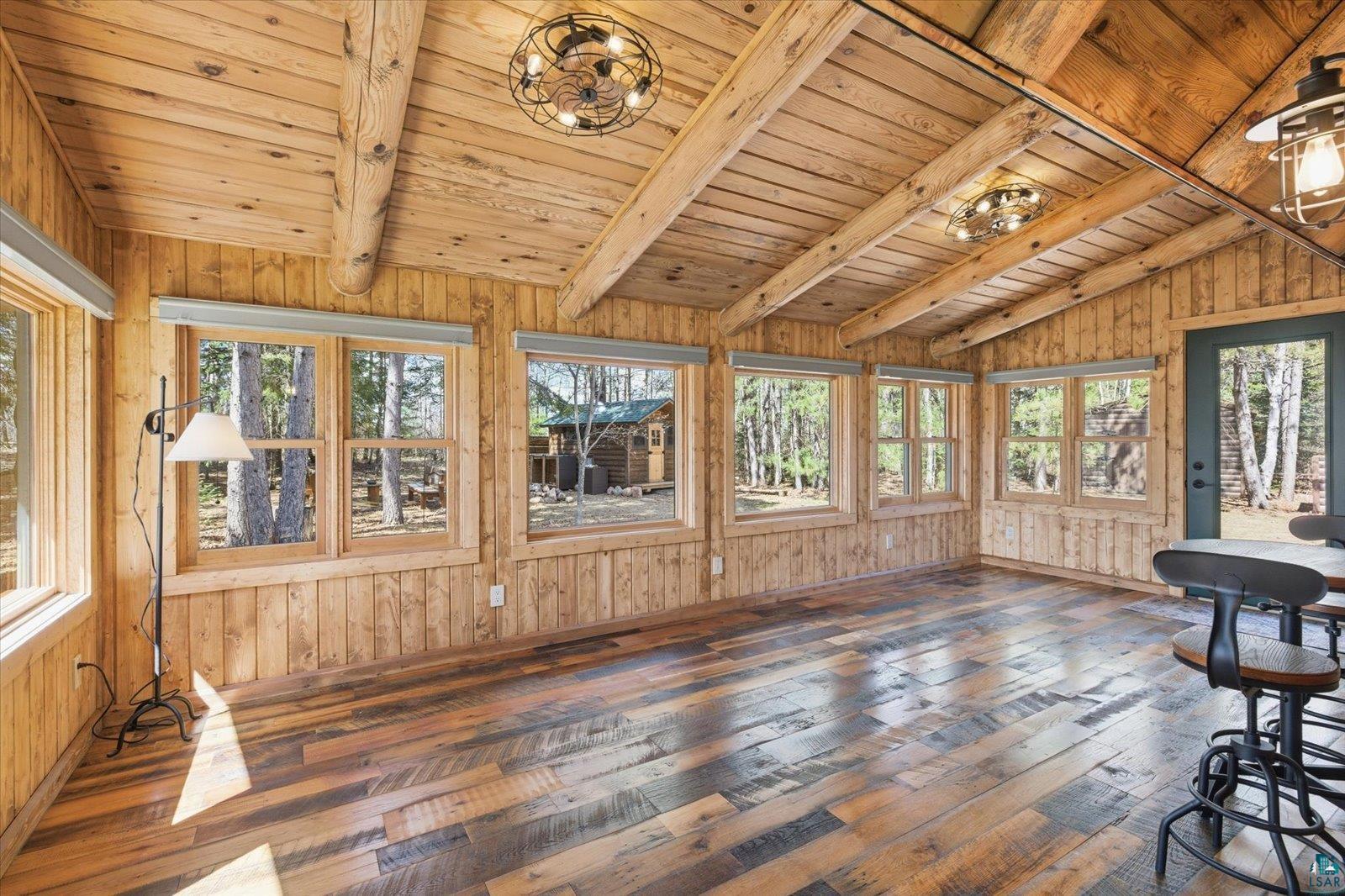 7185 Giants Ridge Road Embarrass, MN 55732 - Photo 13 of 47 Spacious room featuring wood-finish flooring, plank wood walls, and a vaulted ceiling with exposed wood beams