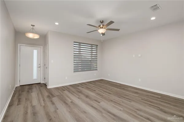 a view of empty room with wooden floor and fan
