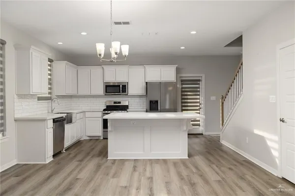 a kitchen with white cabinets stainless steel appliances a sink and a stove