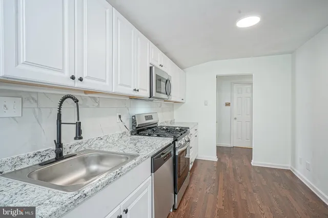 a kitchen with granite countertop a sink stove and cabinets