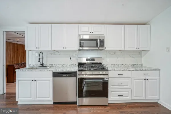 a kitchen with granite countertop white cabinets and stainless steel appliances