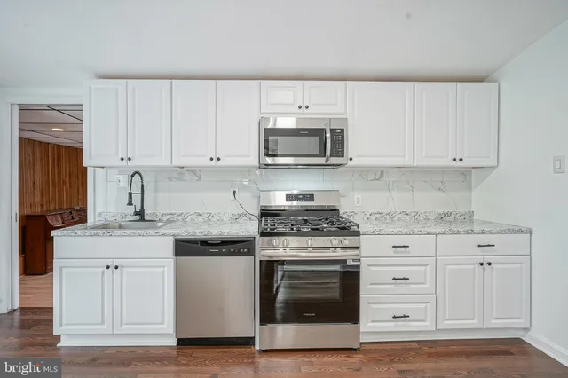 a kitchen with granite countertop white cabinets and stainless steel appliances
