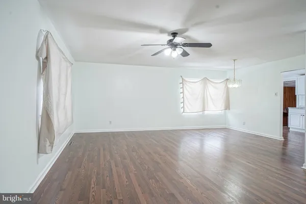 an empty room with wooden floor fan and windows