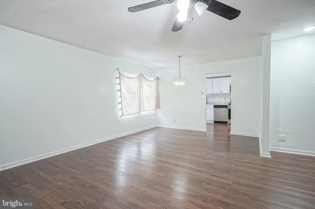 an empty room with wooden floor chandelier and windows