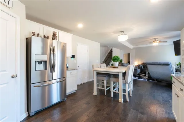 a kitchen with stainless steel appliances a refrigerator a stove a dining table and chairs with wooden floor