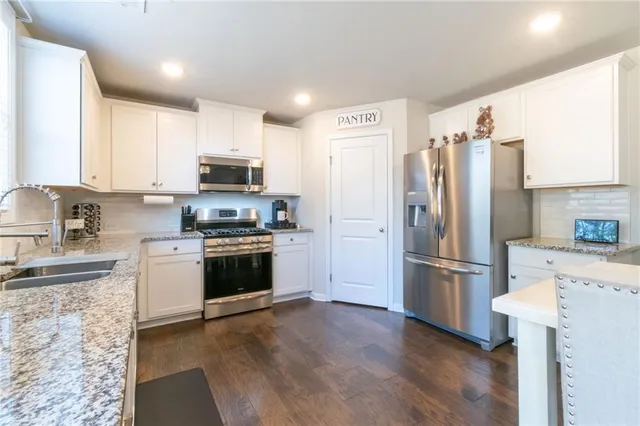 a kitchen with granite countertop a refrigerator stove and wooden floor