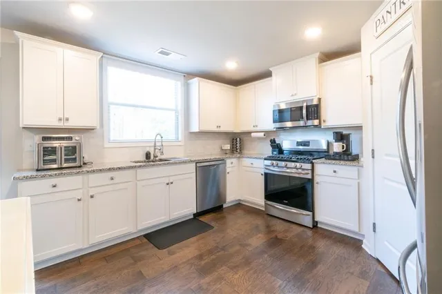 a kitchen with granite countertop white cabinets and white stainless steel appliances