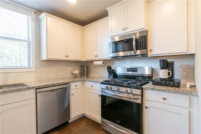 a kitchen with stainless steel appliances granite countertop grey cabinets a sink and a stove