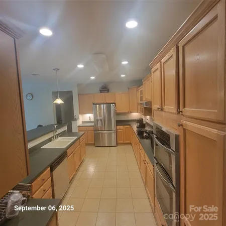 a large kitchen with stainless steel appliances a large counter top a stove and a refrigerator