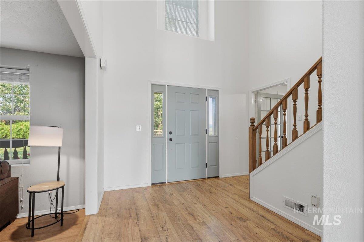 24440 Kenridge Road Caldwell, ID 83607 - Photo 6 of 48 Two-story entryway featuring wood-finish flooring, a light gray front door with sidelights, and a staircase with a wood baluster railing