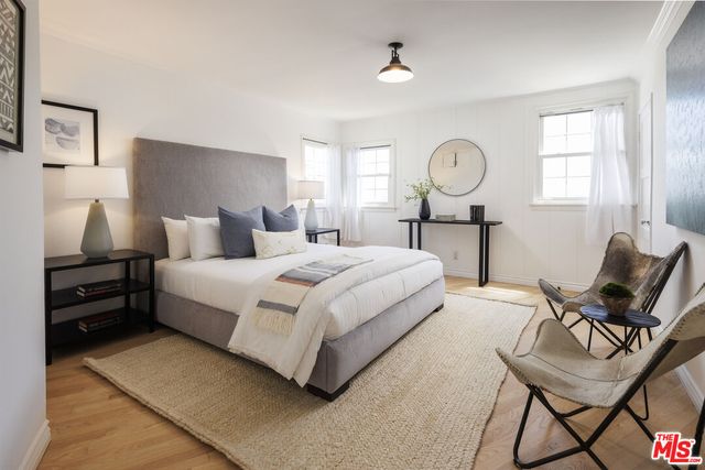 a bedroom with bed and chair with window