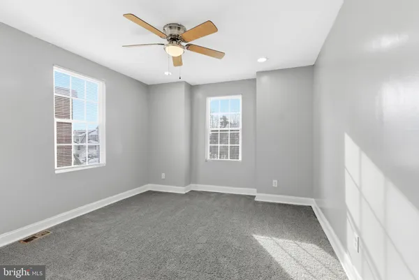 an empty room with windows and fan