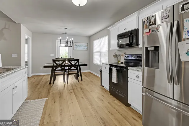 a kitchen with granite countertop a refrigerator a stove top oven a sink dishwasher a dining table and chairs with wooden floor