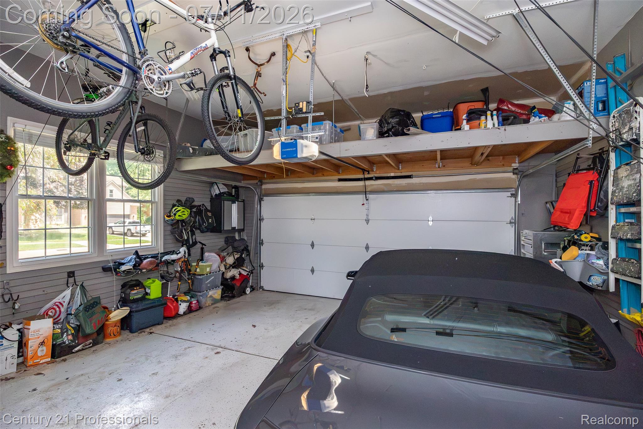 689 Woodfield Way Rochester, MI 48307 - Photo 49 of 61 Spacious garage featuring a white overhead door, multiple windows, built-in shelving, overhead storage, and ceiling-mounted storage racks