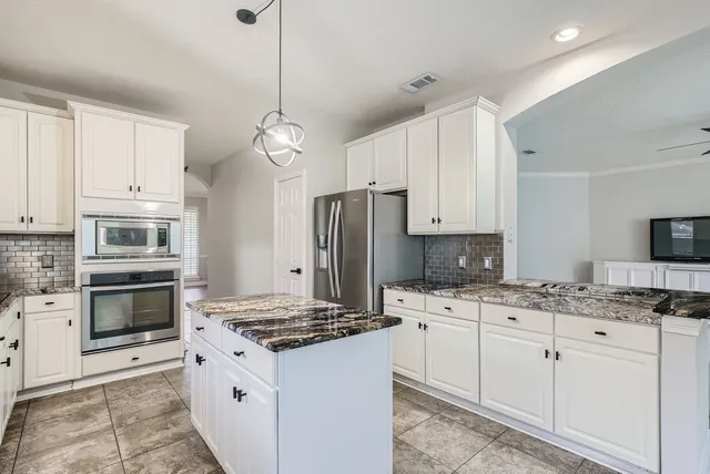 a kitchen with granite countertop a sink stove and refrigerator