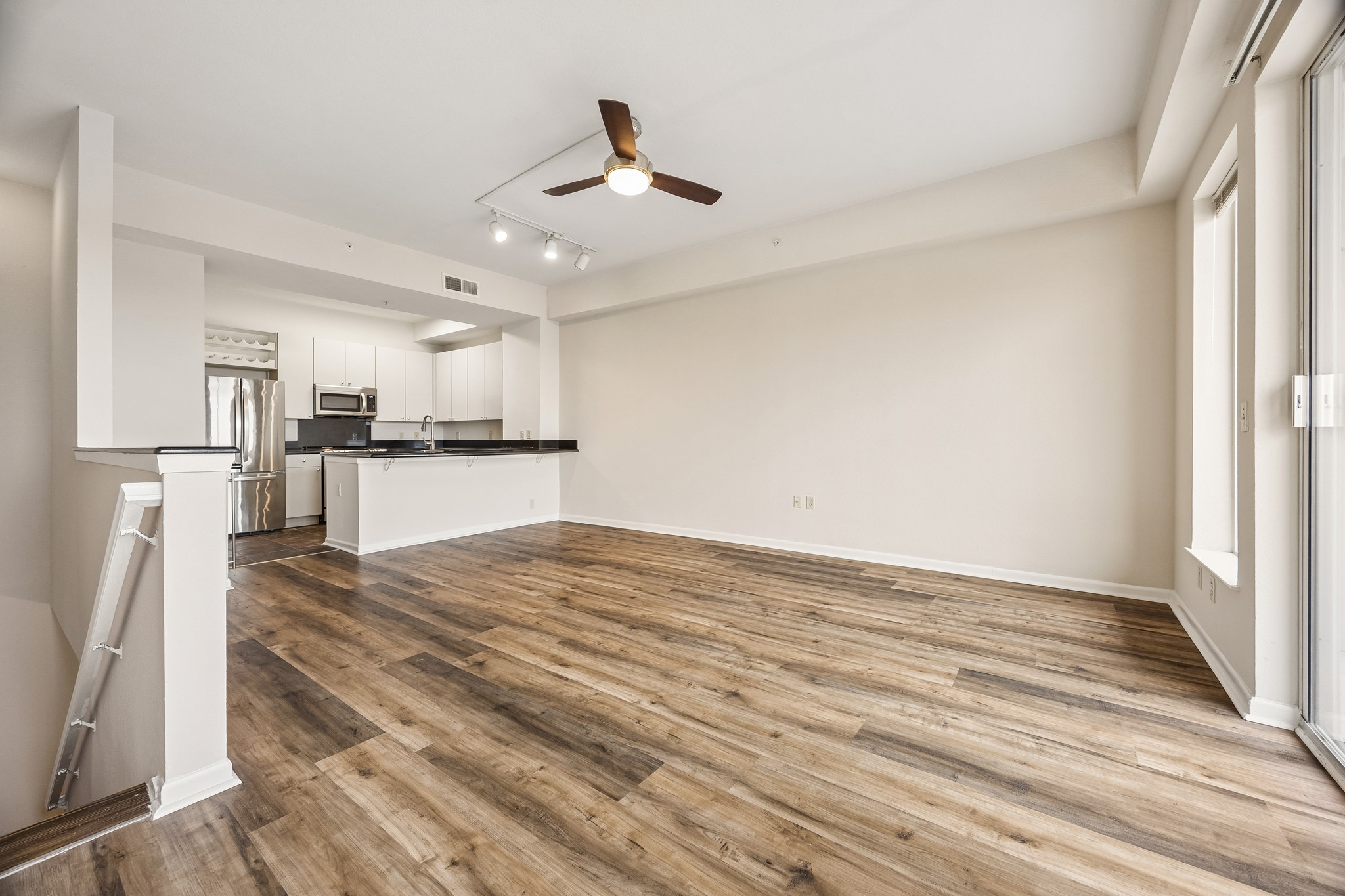 Dramatic open living area showing kitchen, doors to balcony and entry to stairs.