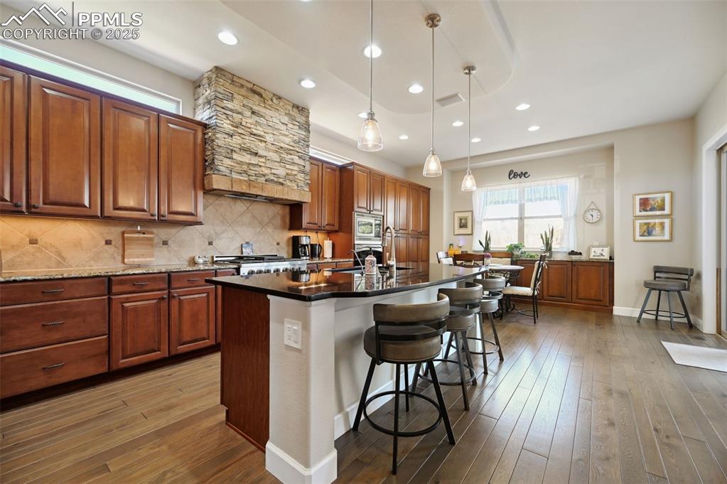 1724 Valley Stream Court Colorado Springs, CO 80921 - Photo 10 of 49 a kitchen with stainless steel appliances granite countertop wooden floors stove top oven with a dining table and chairs