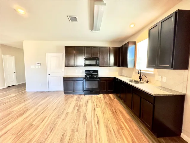 a kitchen with granite countertop a sink wooden floor and stainless steel appliances