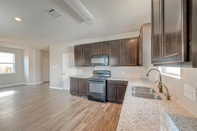 a view of kitchen with kitchen island a sink wooden floor and living room