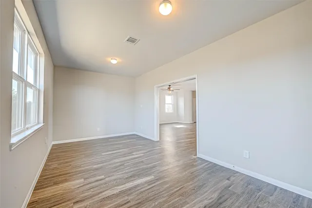 a view of an empty room with wooden floor and a window