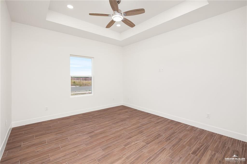 2110 Trinity Street Donna, TX 78537 - Photo 11 of 17 an empty room with wooden floor ceiling fan and windows