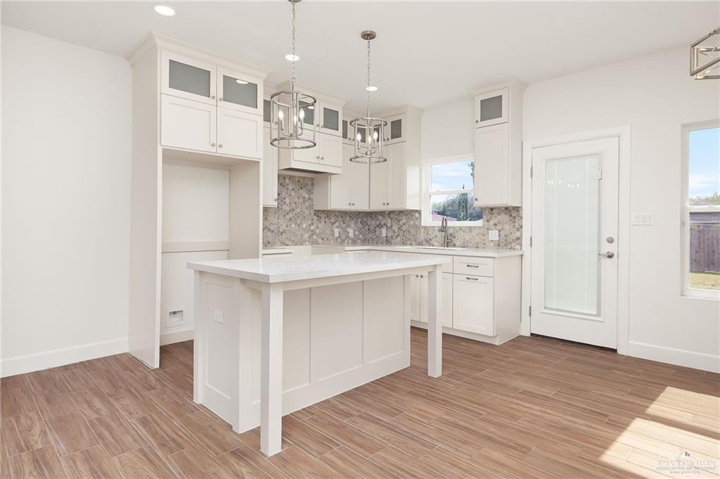 2110 Trinity Street Donna, TX 78537 - Photo 7 of 17 a large white kitchen with kitchen island a sink dishwasher a stove and white cabinets with wooden floor