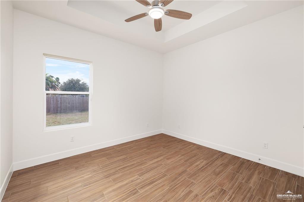 2110 Trinity Street Donna, TX 78537 - Photo 9 of 17 an empty room with wooden floor chandelier fan and windows