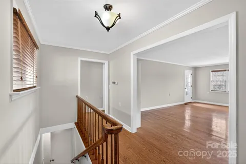 a view of an empty room with wooden floor and stairs