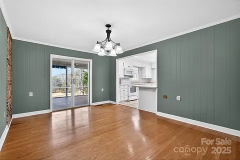 a view of a livingroom with wooden floor and kitchen