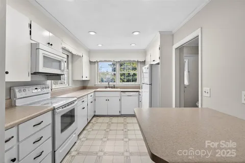 a large white kitchen with stainless steel appliances granite countertop a stove a sink dishwasher and a refrigerator