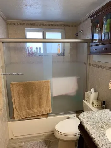 a bathroom with a granite countertop sink mirror vanity and toilet