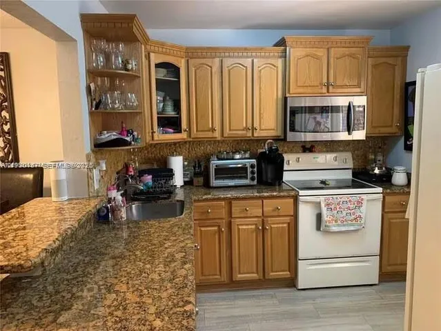 a kitchen with stainless steel appliances granite countertop a stove a sink and a microwave