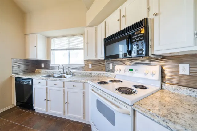 a kitchen with cabinets appliances a sink and a window