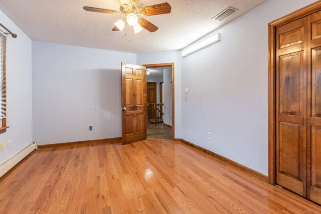 a view of a hallway with wooden floor and a cabinet