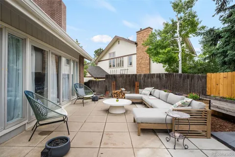 a view of a backyard with couches plants and large trees