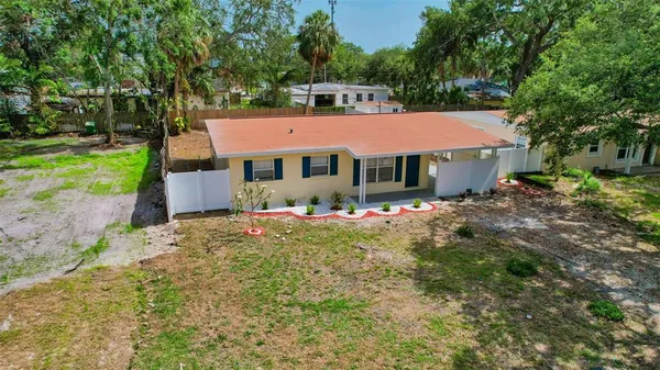 an aerial view of residential house with outdoor space and trees all around
