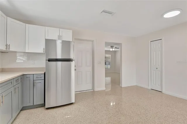 a view of a kitchen with refrigerator and white cabinets