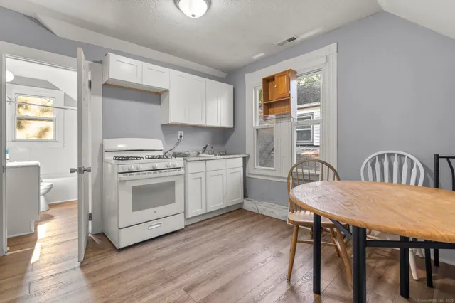 a kitchen with a table chairs a sink dishwasher stove and cabinets
