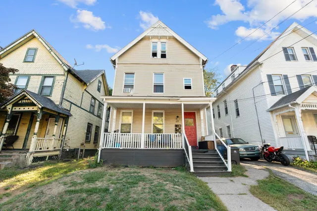a view of a white house with large windows and a yard