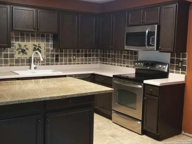a kitchen with sink a microwave a stove and cabinets