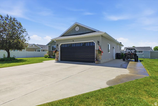 772 East 600 South Preston, ID 83263 - Photo 4 of 35 Side-load garage with a dark panel door, light grey siding, and stone accents