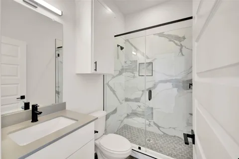 a bathroom with a sink vanity granite toilet and shower