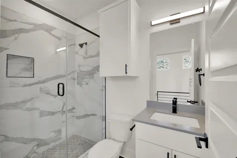 a bathroom with a granite countertop sink mirror vanity and toilet