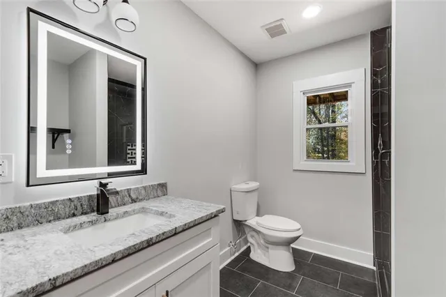 a bathroom with a granite countertop toilet a sink and a mirror