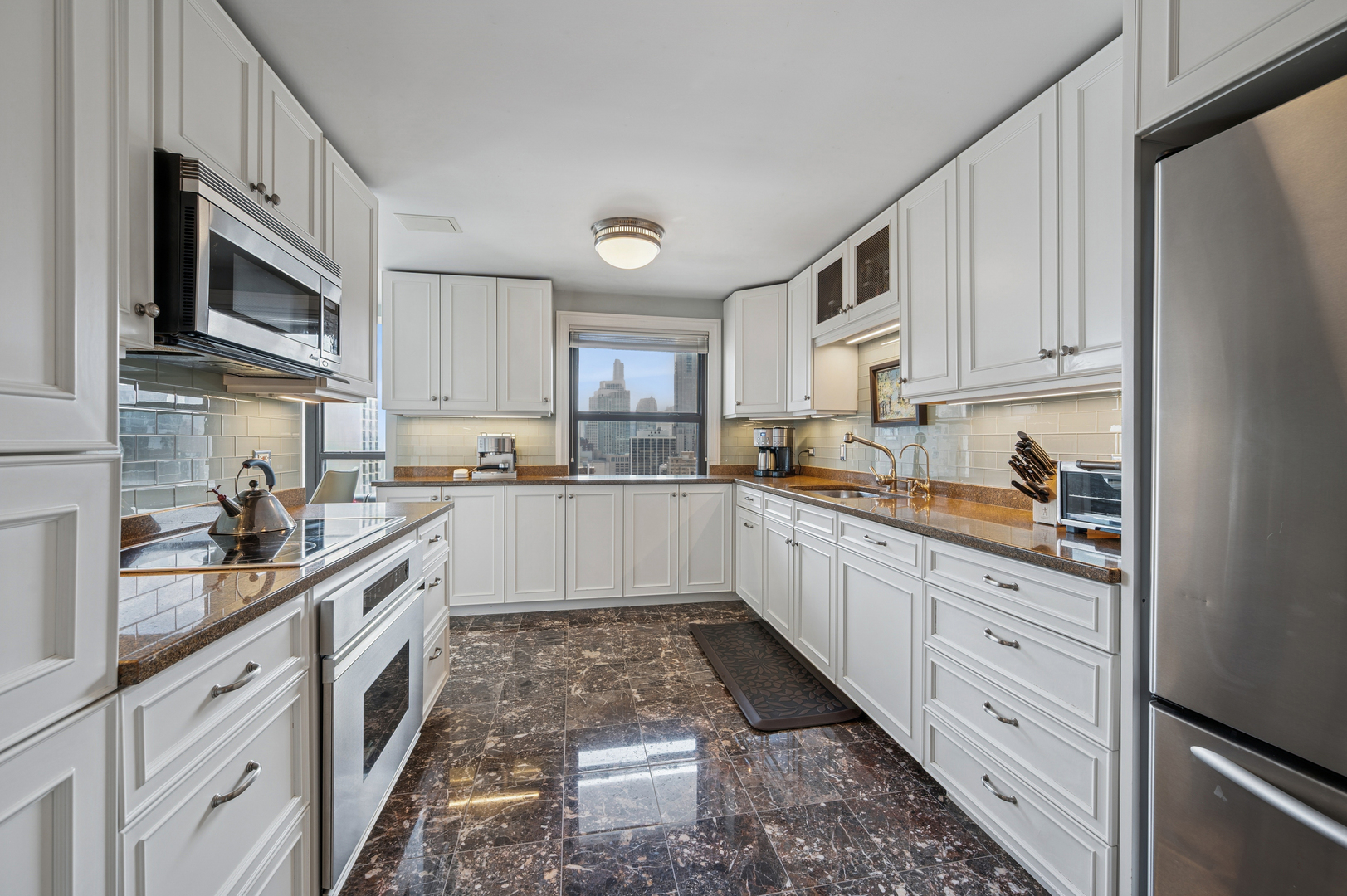 1313 North Ritchie Court, Unit 2701 Chicago, IL 60610 - Photo 11 of 33 a large kitchen with stainless steel appliances granite countertop a stove a sink dishwasher and a refrigerator with wooden cabinets